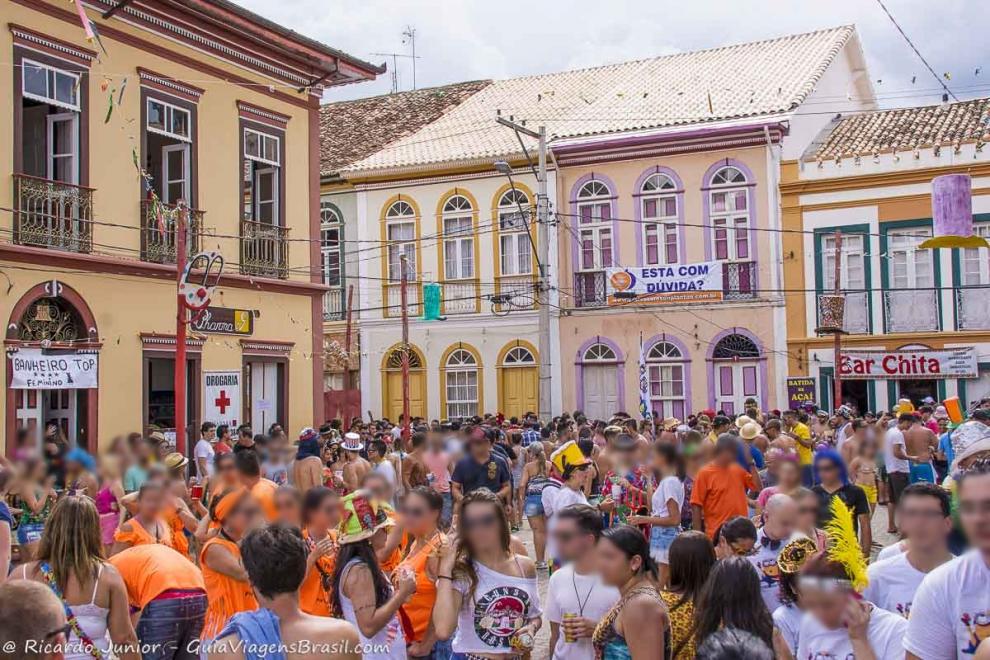 Imagem de pessoas nas ruas e casarões na praça da cidade.